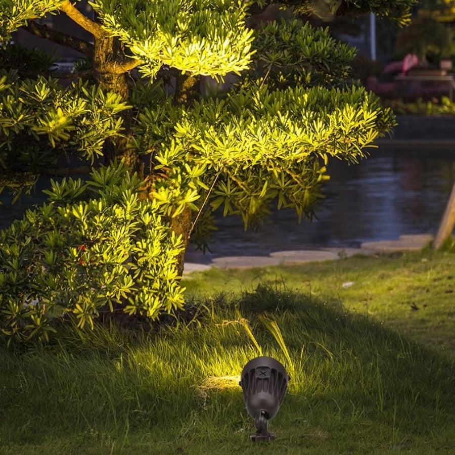 LED Flood Light fixture on grass with greenery and water in the background