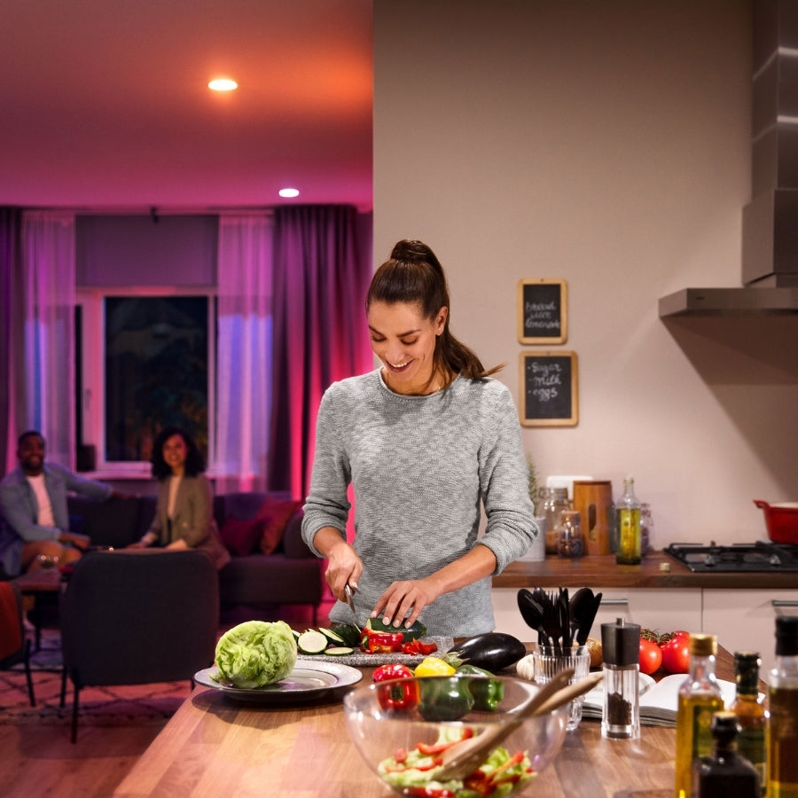 Woman preparing food in a kitchen with a living room in the background