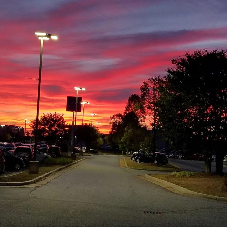 Parking lot with cars at dusk under a vibrant red and orange sky.