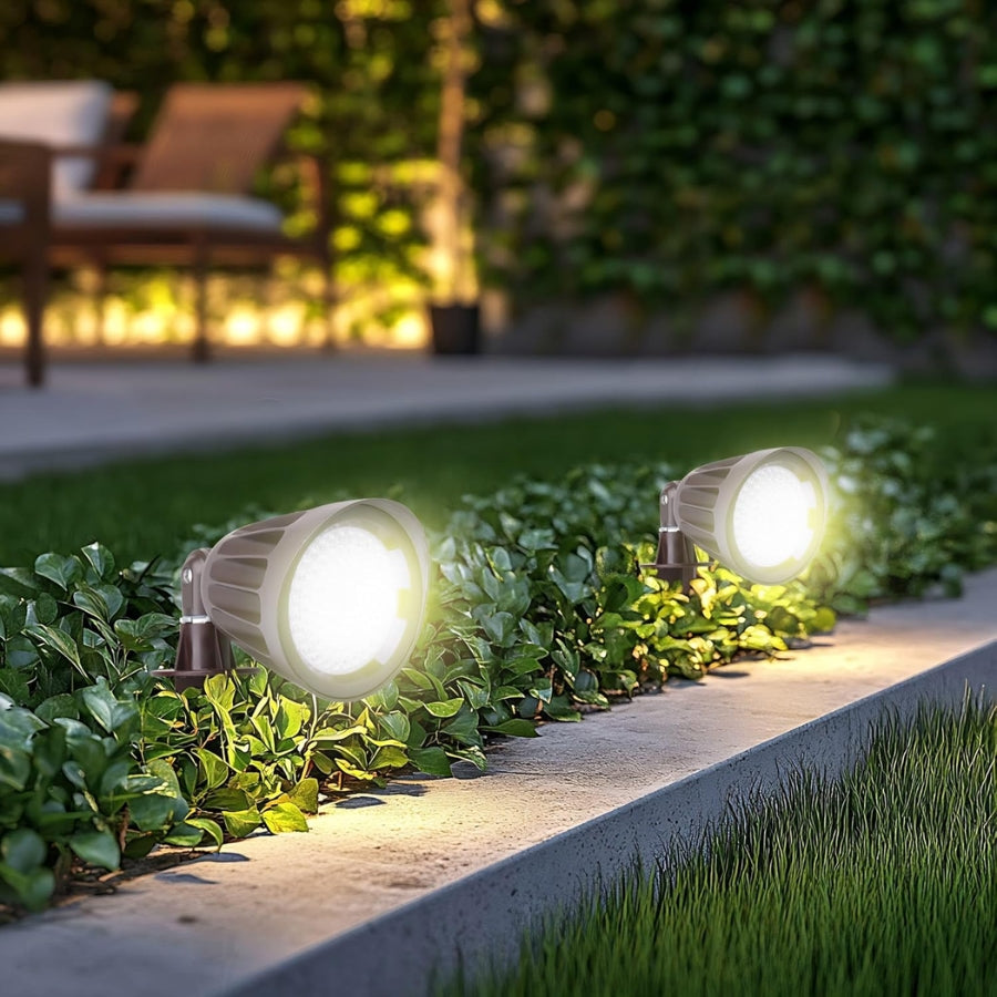 Two outdoor garden lights illuminating a pathway surrounded by greenery.